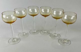 A set of amber tinted and clear glass tall stemmed wine glasses attributed to Peter Behrens (German,
