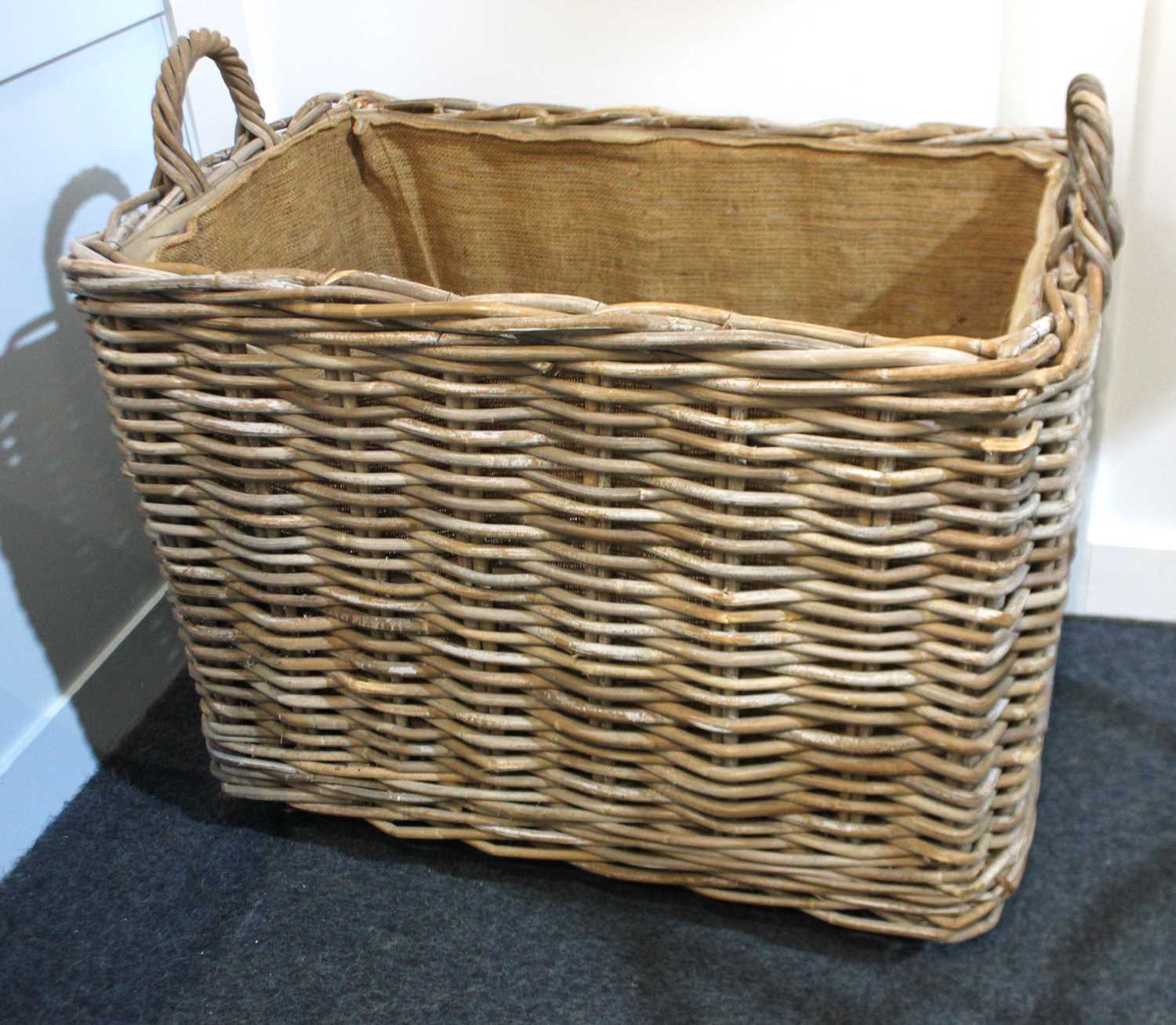 A large rectangular wicker two handled basket on castors 66cm high, 73cm wide