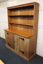 A pine dresser, two tier plate rack with wide boarded back, the base with two panelled cupboard