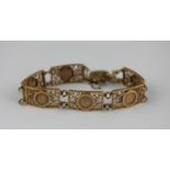 A 9ct gold bracelet in a curved and pierced rectangular design mounted with Peso style coins, with a