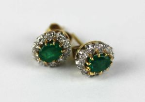A pair of 18ct gold emerald and diamond oval cluster ear studs each claw set with an oval cut