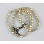 A single row necklace of graduated cultured pearls on a cultured pearl and colourless gem set clasp