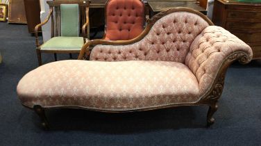 A Victorian chaise longue with scroll carved frame and button upholstered back, on cabriole legs and