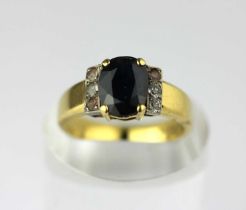 An 18ct gold ring claw set with an oval cut dark sapphire between colourless gem set three stone