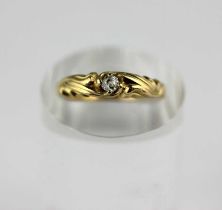 A gold and diamond single stone ring, claw set with a cushion shaped diamond between scrolled