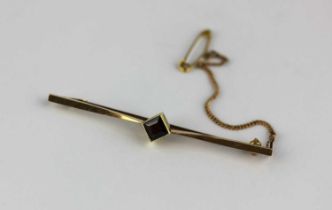 A gold and garnet single stone bar brooch mounted with a square cut garnet, detailed '15ct',