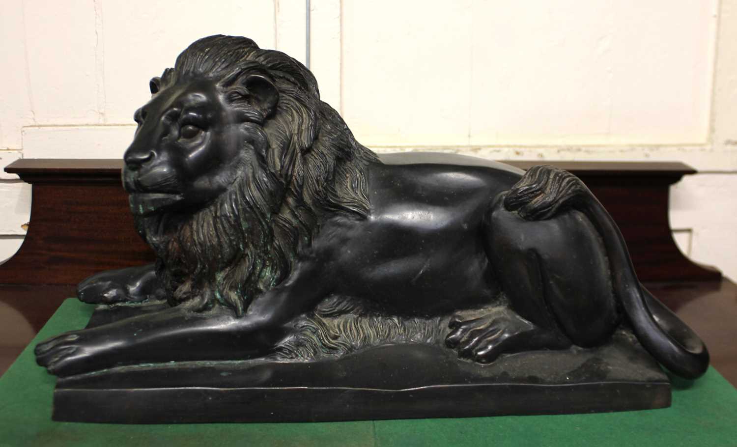 A cast bronze model of a recumbent lion 53cm