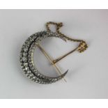 A late Victorian gold backed and silver set diamond crescent brooch in a three row design mounted
