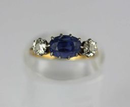 A gold, sapphire and diamond three stone ring, claw set with the oval cut sapphire between two