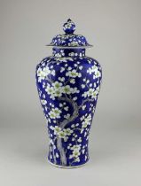 A Chinese porcelain vase and cover decorated with prunus blossom on blue ground, character marks