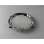 A George VI silver circular card tray with gadrooned pie crust border on three scroll feet, maker