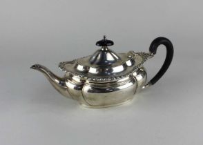 A silver teapot of oval shape with a gadrooned borer, an ebonised handle and finial. Maker Elkington