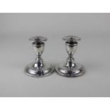 A pair of Edward VII silver dwarf candlesticks with vase shaped sconces and removable drip trays