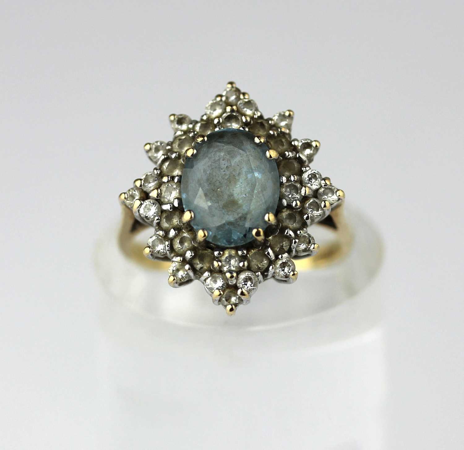 A 9ct gold synthetic pale blue and colourless oval cluster ring, claw set with the oval cut