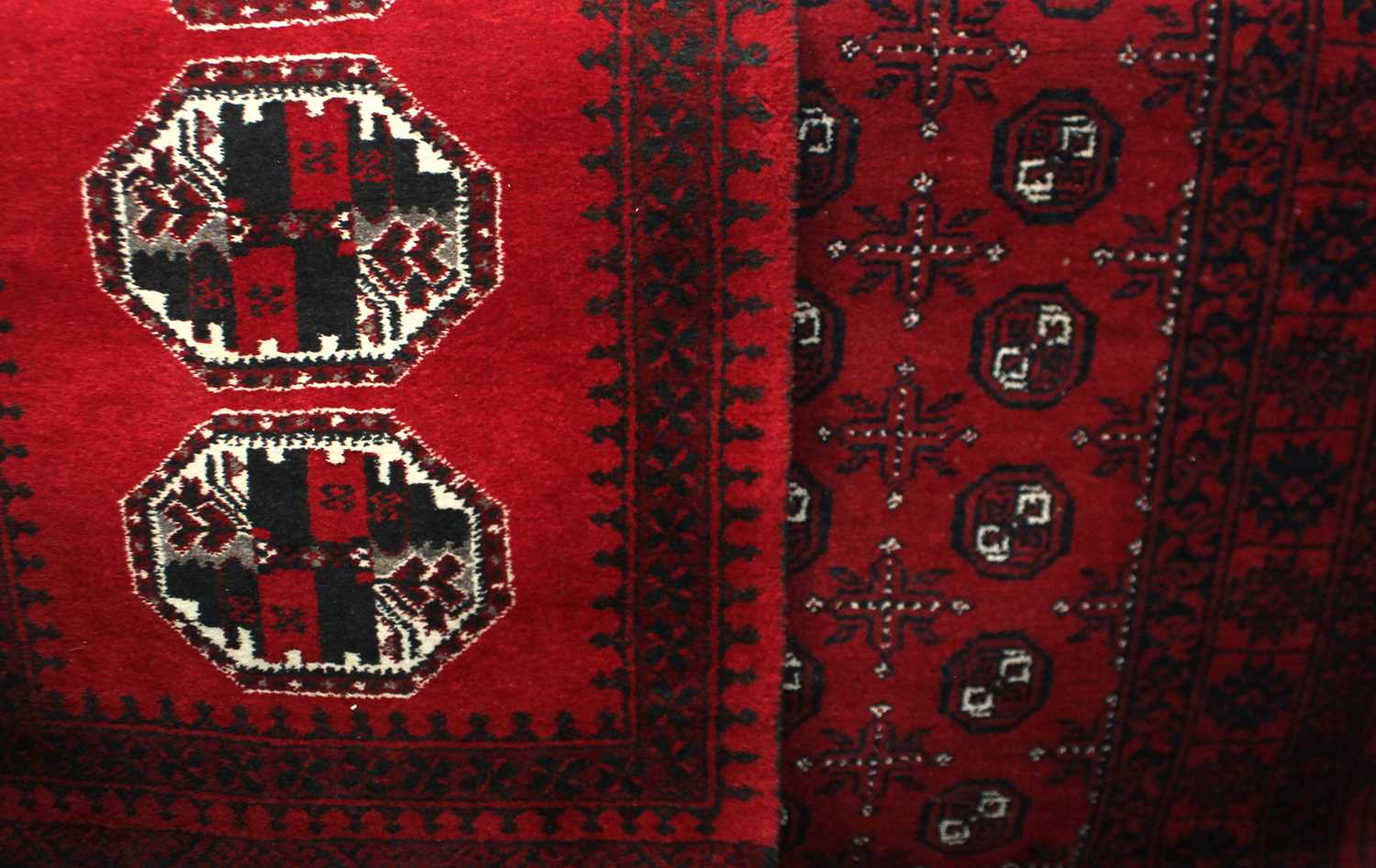 A Bokhara rug, red ground with two rows of guls within wide border 105cm by 200cm, and a similar rug