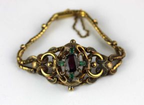 A Victorian gold, emerald and garnet bracelet mounted with a central oval cut garnet within a
