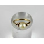 An Mikimoto 18ct gold ring mounted with a single cultured pearl between two circular cut diamonds,