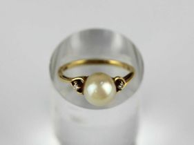 An Mikimoto 18ct gold ring mounted with a single cultured pearl between two circular cut diamonds,