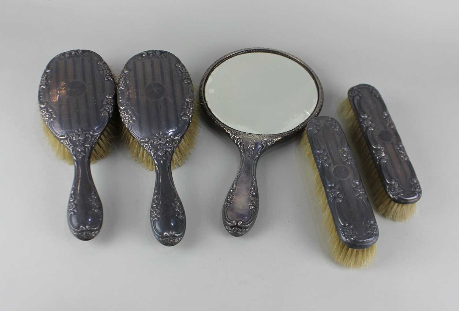 A George V silver five piece silver dressing table set comprising of two pairs of brushes and a hand