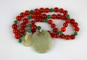 A carved jade oval pendant, later mounted to a cornelian and aventurine bead necklace