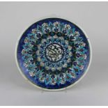 A Turkish Kutahya pottery plate decorated in blue, red, green and turquoise with Islamic inscription