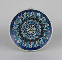 A Turkish Kutahya pottery plate decorated in blue, red, green and turquoise with Islamic inscription