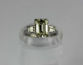 A diamond ring claw set with the cut cornered rectangular emerald cut diamond between baguette