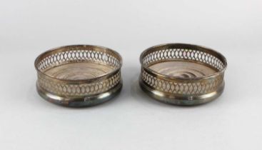 A pair of modern silver bottle coasters with pierced sides, turned wooden bases, maker C J Vander,