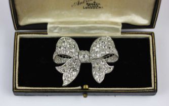 A diamond brooch designed as a tied bow mounted with cushion shaped diamonds of varying sizes,
