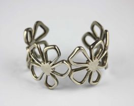 A Tiffany & Co silver bangle pierced as a row of four flower heads with a pouch and box