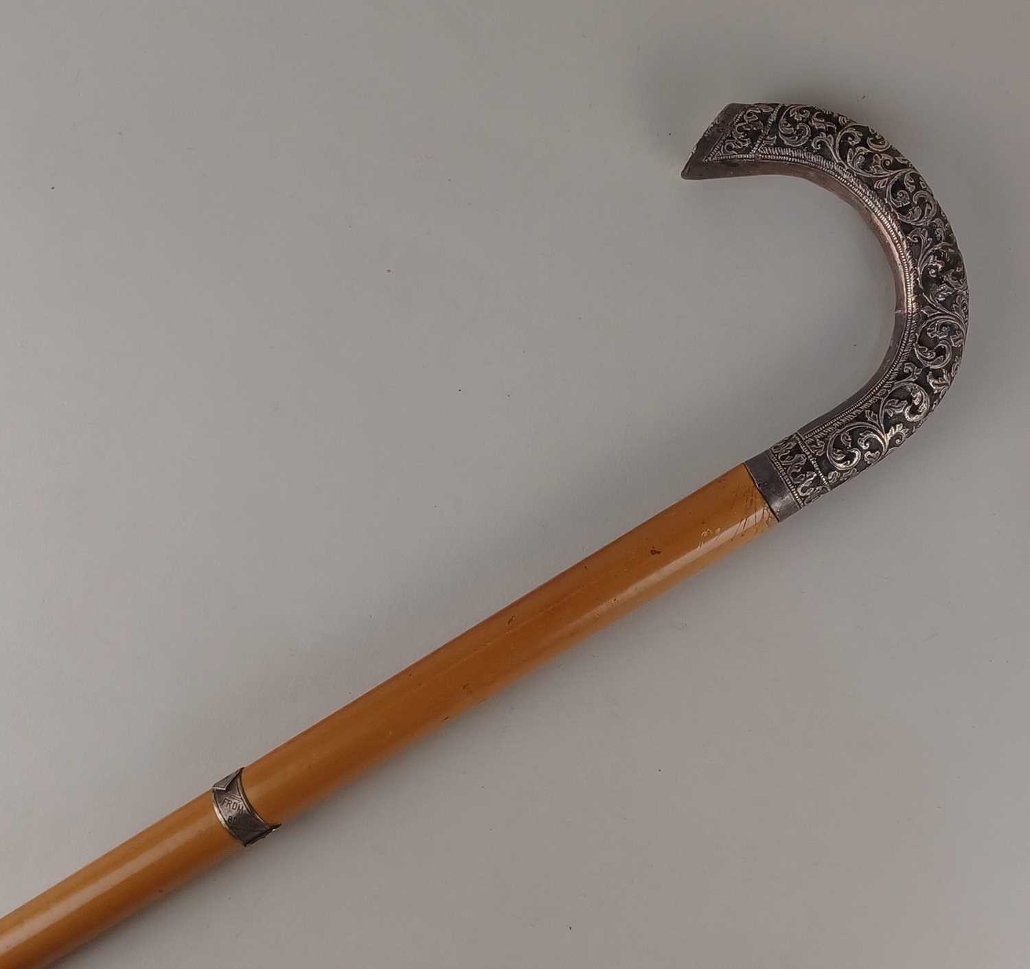 An early 20th century Indian walking cane the white metal mounted handle with embossed floral