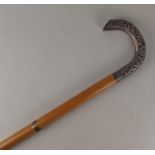 An early 20th century Indian walking cane the white metal mounted handle with embossed floral