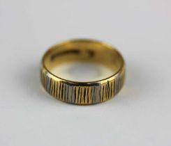 An 18ct two colour gold wedding ring with textured decoration, Sheffield 1977, ring size K 1/2, 4.