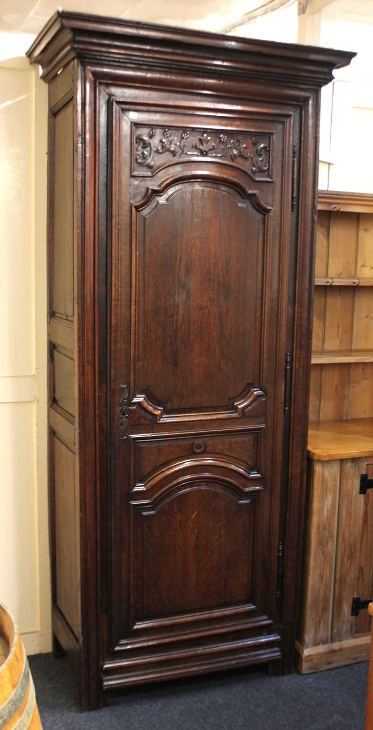 A French oak bonnetiere cabinet with moulded cornice and single door with arched and floral carved