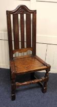 An 18th century oak hall chair, with fleur de lis carved arched top rail, dished seat, turned and