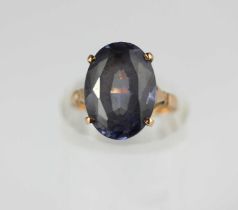 A gold ring claw set with an oval cut synthetic corundum imitation Alexandrite, unmarked, probably
