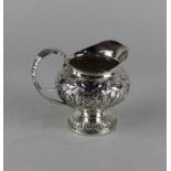 A George III silver milk jug baluster shape with embossed scrolling flowers and foliage, maker