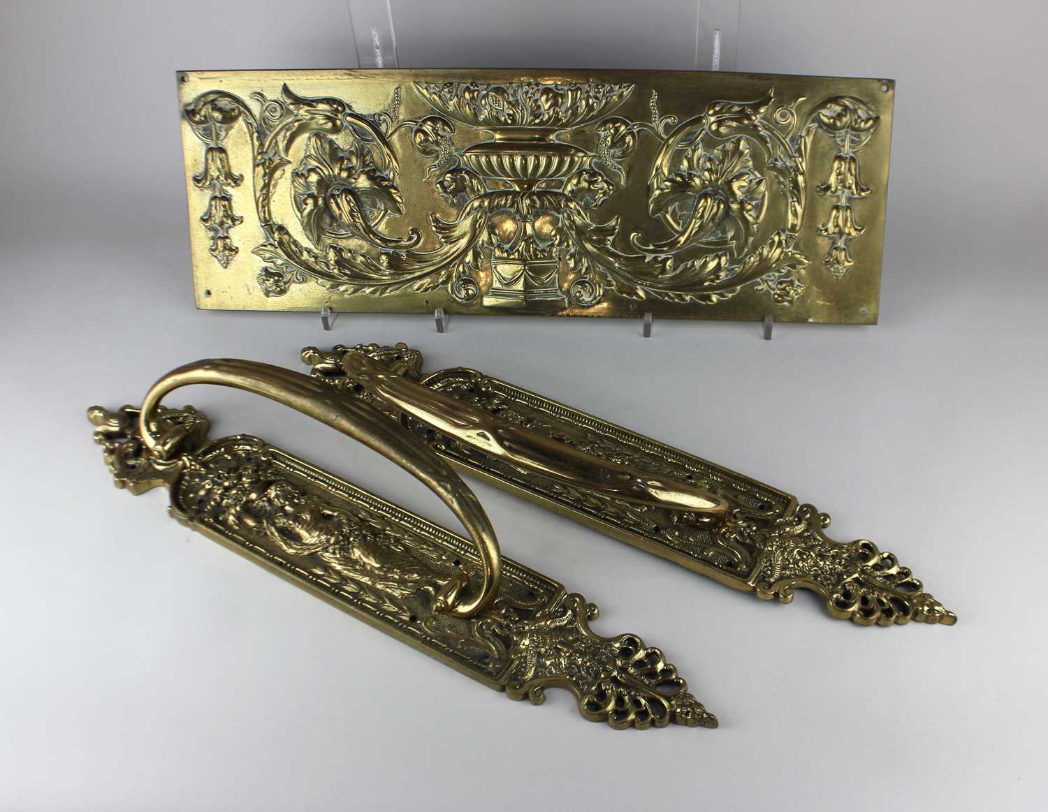 A pair of large brass door handles decorated with a classical figure holding a basket of flowers
