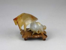 A Chinese carved agate model of a goldfish on wooden stand in the form of a lily pad 7cm high
