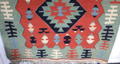 A Kilim rug, red ground, with geometric motifs in green, red, buff and dark blue 117cm by 166cm