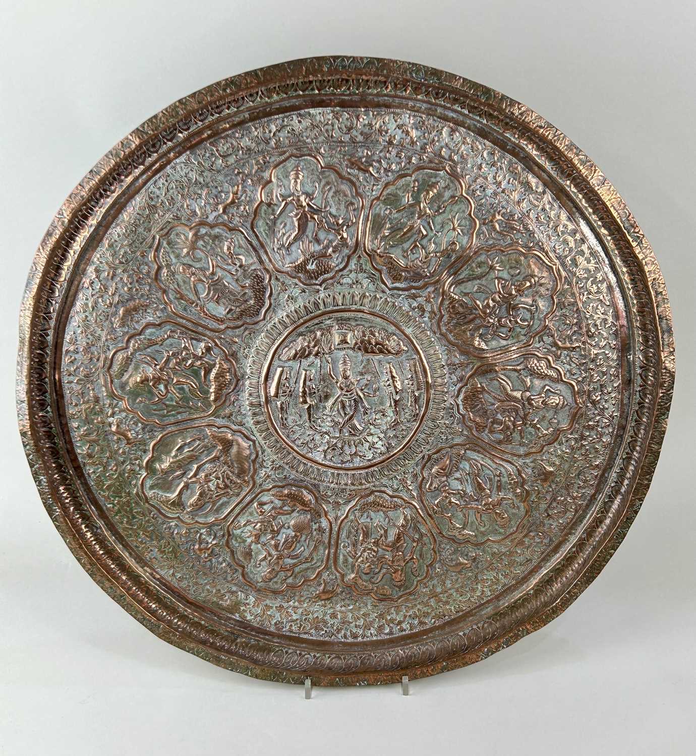 A 19th century Indian Mughal copper charger decorated in repousse and chasing portraying the