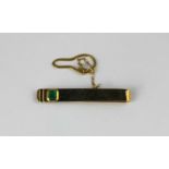 A gold and emerald single stone tie slide mounted with a rectangular cut emerald with a button