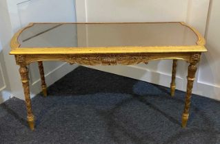 A giltwood and gesso coffee table the rectangular mirror top enclosed by a frieze moulded in