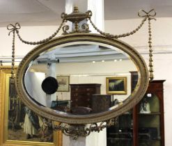 A 19th century gilt and gesso wall mirror with oval mirror plate surmounted by urn and ribbon tied