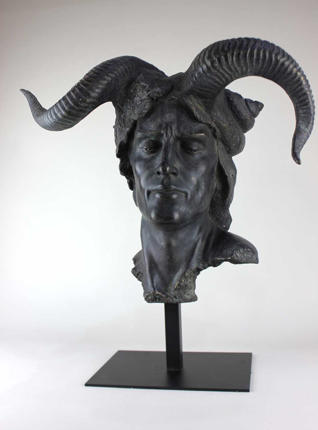 A contemporary bronzed sculpture modelled as a Demon mask, raised on a metal stand, overall combined