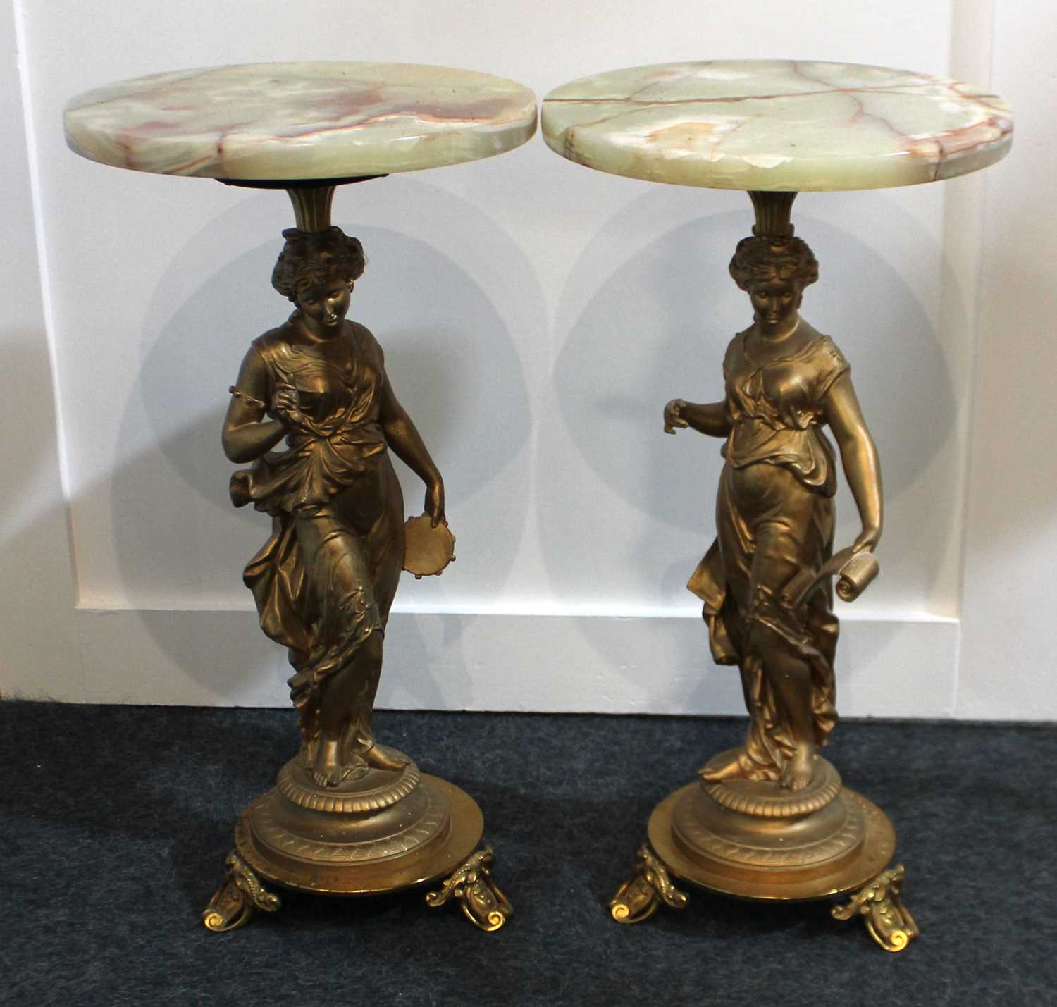 A pair of gilt metal and onyx figural side tables circular top on classical figure support to