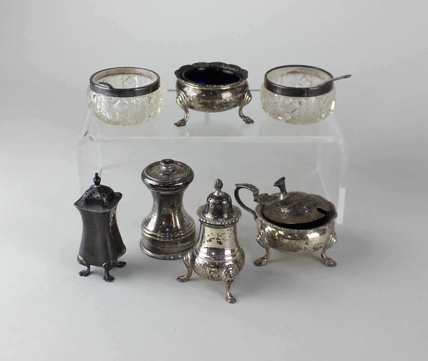 A modern silver three piece cruet set of mustard pot, salt with blue glass liners, and a pepper pot,