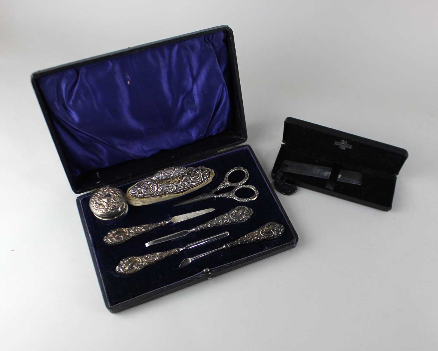 A cased George V silver manicure set comprising five various tools, silver topped glass pot and a