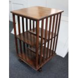 An early 20th century oak revolving bookstand two open tiers with slatted sides on swivel base,