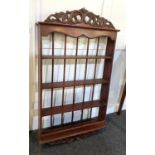 A mahogany wall rack the carved surmount above three shelves with spindle back, 99cm by 56cm